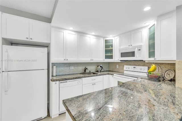 kitchen with sink, dark stone countertops, white cabinets, and white appliances