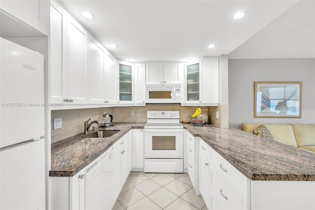 kitchen featuring white appliances, light tile patterned floors, white cabinets, glass insert cabinets, and dark stone countertops