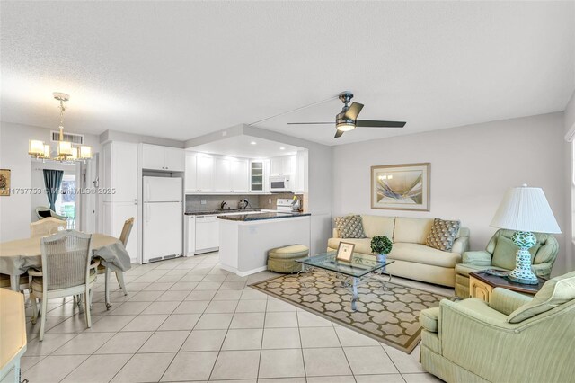 living room with ceiling fan with notable chandelier, a textured ceiling, and light tile patterned floors