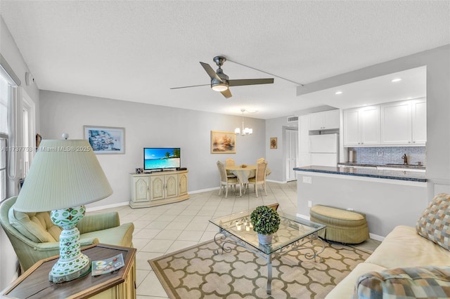 tiled living room featuring sink, ceiling fan with notable chandelier, and a textured ceiling