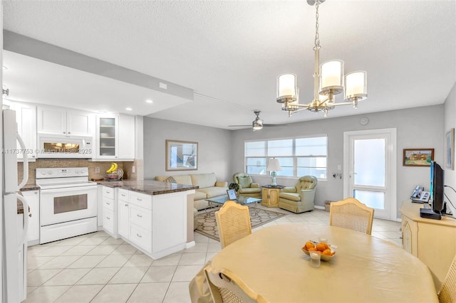 kitchen with decorative light fixtures, white cabinets, light tile patterned floors, kitchen peninsula, and white appliances