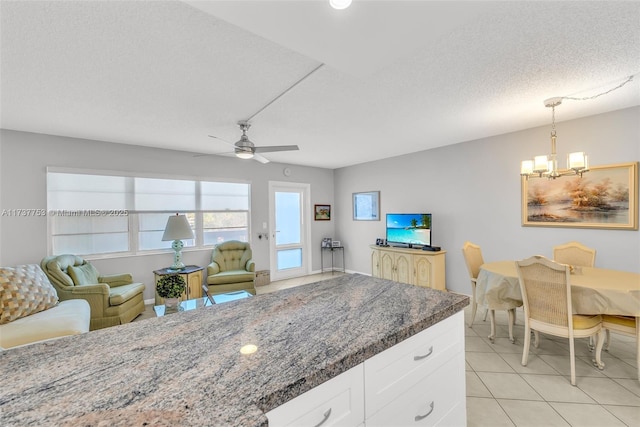 kitchen featuring ceiling fan with notable chandelier, pendant lighting, dark stone countertops, white cabinets, and a textured ceiling