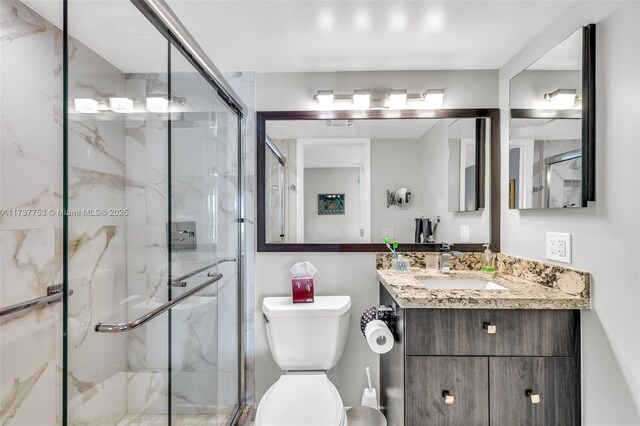 bathroom featuring vanity, a shower with door, and toilet