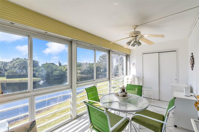 sunroom / solarium featuring a water view and ceiling fan