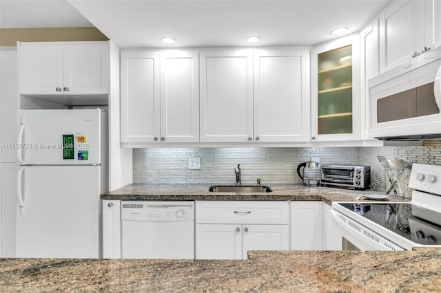 kitchen with white appliances, a toaster, white cabinets, glass insert cabinets, and a sink