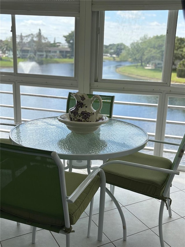 dining area featuring a water view, a healthy amount of sunlight, and light tile patterned flooring