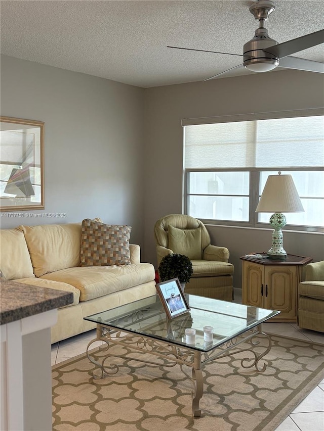 living area with light tile patterned flooring, ceiling fan, and a textured ceiling