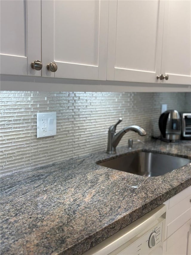 interior details featuring white cabinetry, decorative backsplash, and a sink