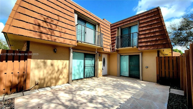 rear view of house featuring a balcony and a patio