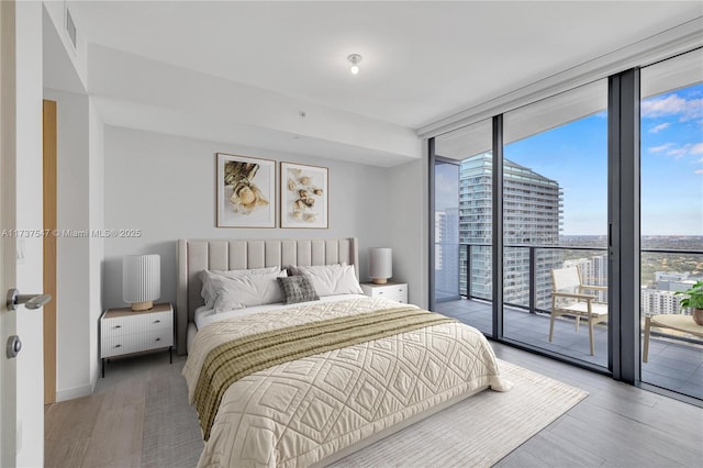 bedroom featuring expansive windows, access to exterior, and light hardwood / wood-style floors