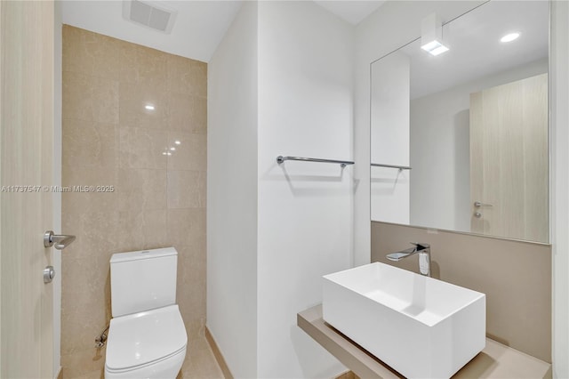 bathroom featuring tile walls, sink, and toilet