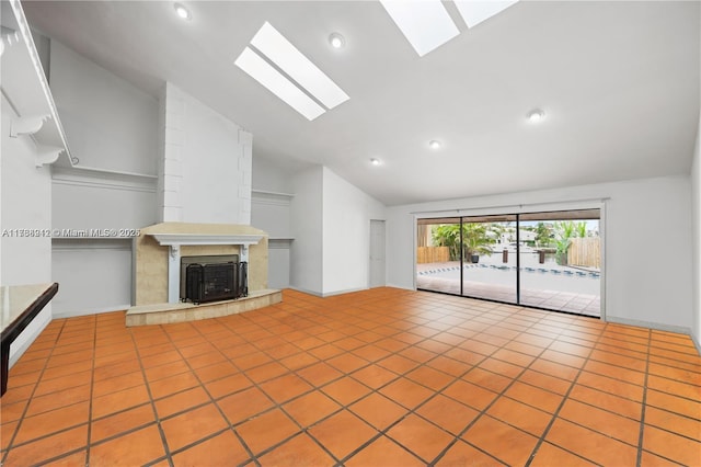 unfurnished living room featuring tile patterned flooring, a tile fireplace, and lofted ceiling with skylight