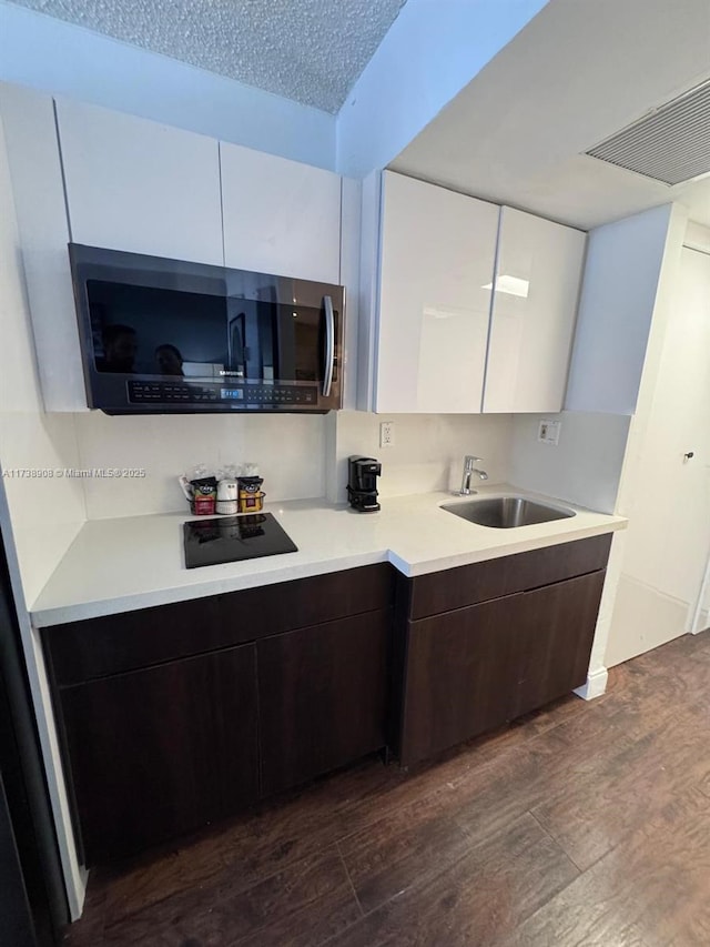 kitchen featuring sink, dark wood-type flooring, white cabinetry, dark brown cabinetry, and a textured ceiling