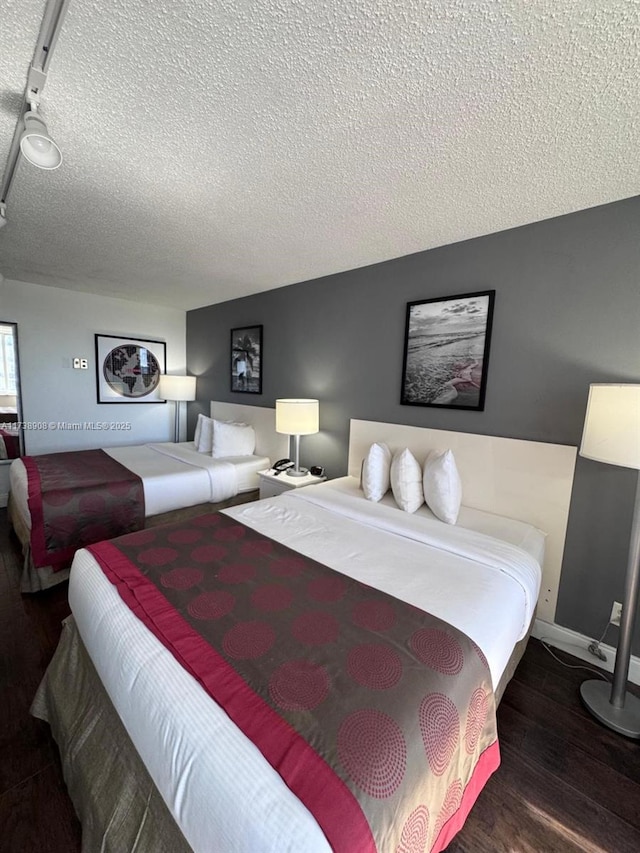 bedroom featuring a textured ceiling and dark hardwood / wood-style flooring