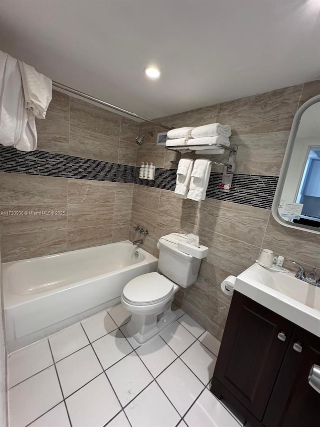 full bathroom featuring toilet, tiled shower / bath, tile walls, vanity, and tile patterned flooring