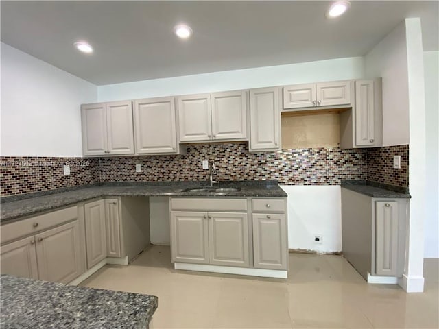 kitchen with dark stone countertops, sink, backsplash, and light tile patterned flooring