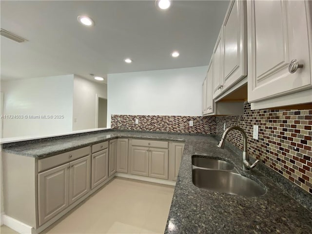 kitchen with tasteful backsplash, sink, and dark stone countertops