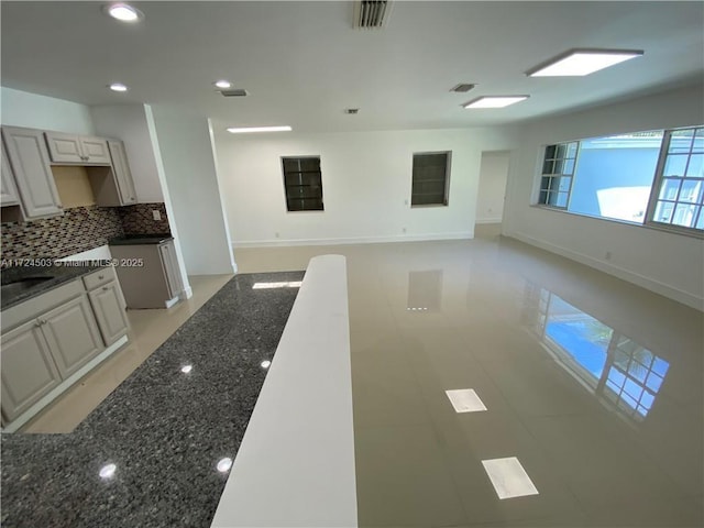 kitchen featuring dark stone countertops, sink, decorative backsplash, and white cabinetry