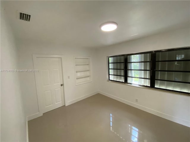 spare room featuring built in shelves