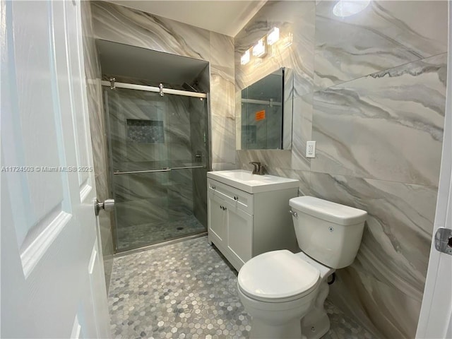 bathroom with vanity, toilet, an enclosed shower, and tile walls