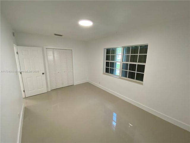 unfurnished bedroom featuring concrete flooring and a closet