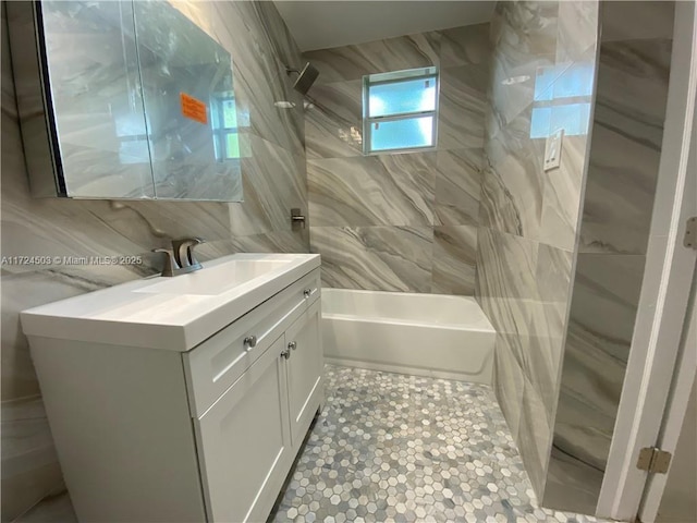 bathroom with vanity, tiled shower / bath combo, tile walls, and backsplash