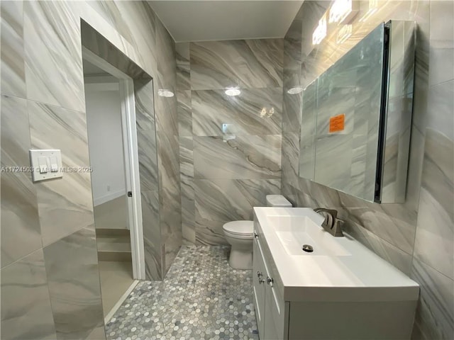 bathroom featuring vanity, toilet, and tile walls