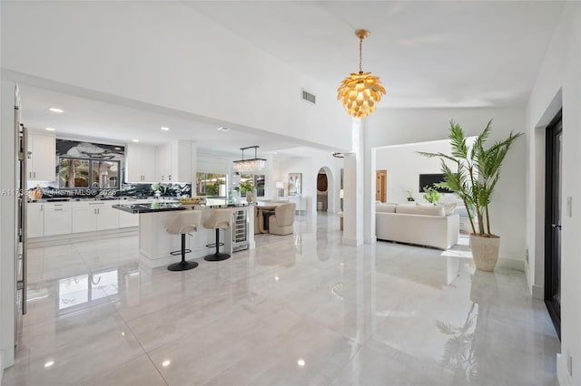 foyer with visible vents, arched walkways, wine cooler, marble finish floor, and a high ceiling