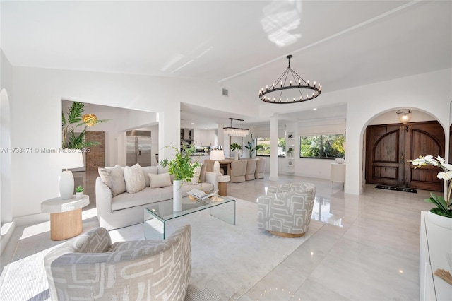 living area with an inviting chandelier, arched walkways, and vaulted ceiling