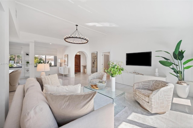 living room with a chandelier, vaulted ceiling, and arched walkways