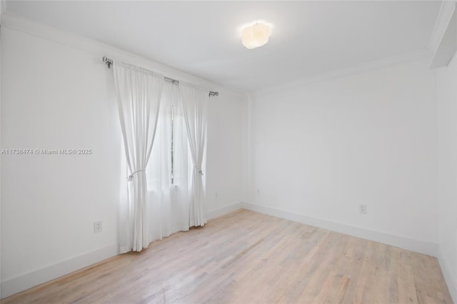 empty room featuring light wood-style flooring, baseboards, and ornamental molding