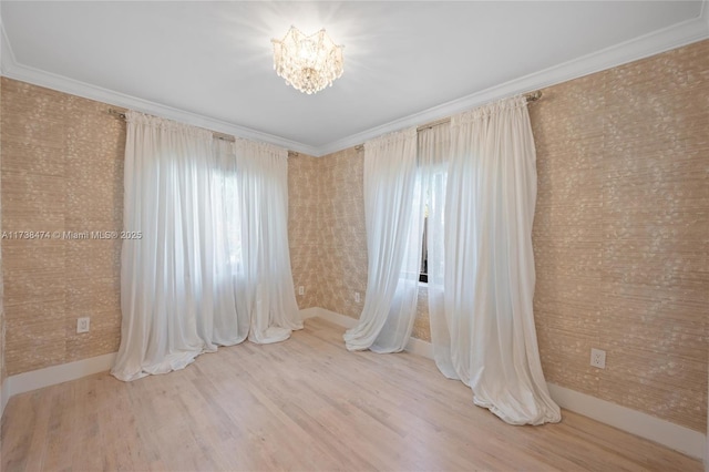 empty room featuring plenty of natural light, a notable chandelier, ornamental molding, and wood finished floors