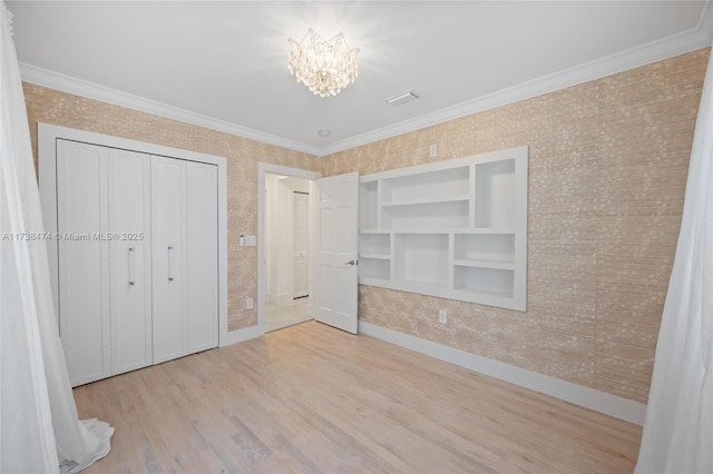 unfurnished bedroom featuring a notable chandelier, ornamental molding, light wood-type flooring, and wallpapered walls