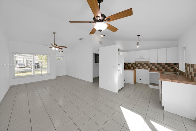 kitchen with sink, light tile patterned floors, white refrigerator, white cabinets, and decorative backsplash