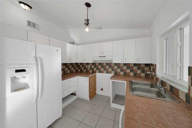 kitchen featuring pendant lighting, sink, white cabinetry, white fridge with ice dispenser, and vaulted ceiling