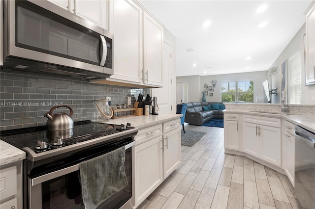 kitchen featuring white cabinetry, decorative backsplash, stainless steel appliances, and light stone counters