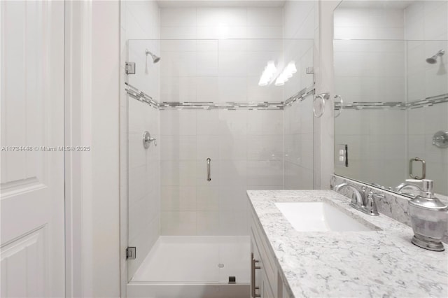 bathroom featuring a shower with door and vanity