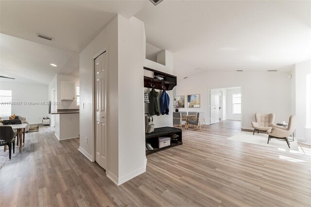 hall with vaulted ceiling and light wood-type flooring