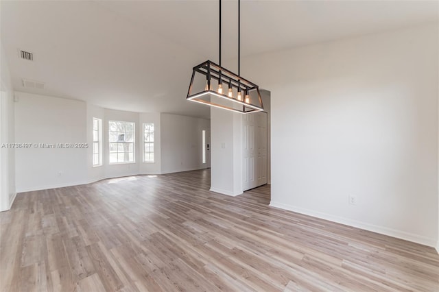 interior space with light wood-type flooring, visible vents, and baseboards