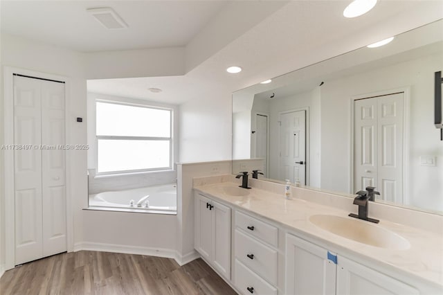 full bath with a sink, double vanity, a closet, and wood finished floors