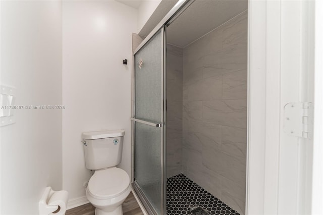 full bathroom featuring a stall shower, baseboards, toilet, and wood finished floors