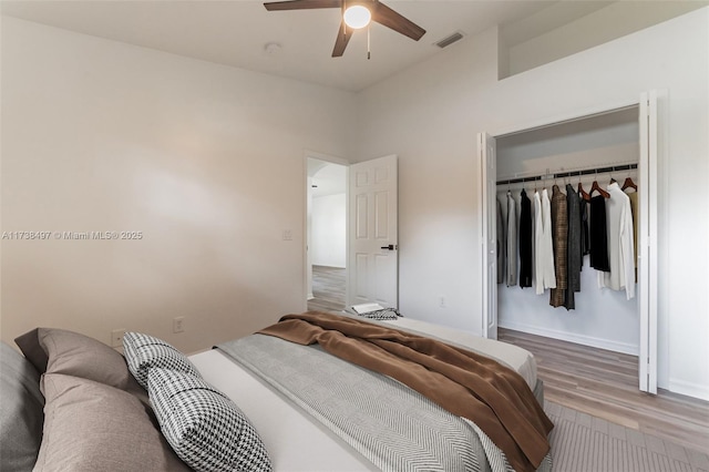 bedroom with baseboards, visible vents, a ceiling fan, wood finished floors, and a closet