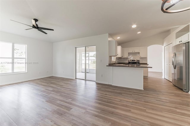 kitchen featuring open floor plan, stainless steel appliances, a peninsula, and white cabinetry