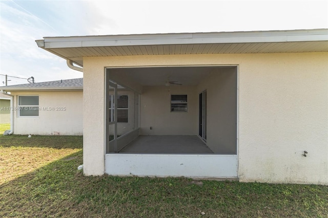 property entrance featuring stucco siding and a yard