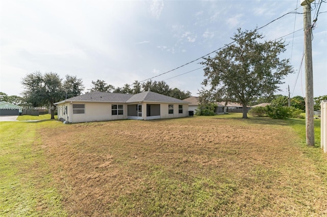 back of property with a lawn and stucco siding