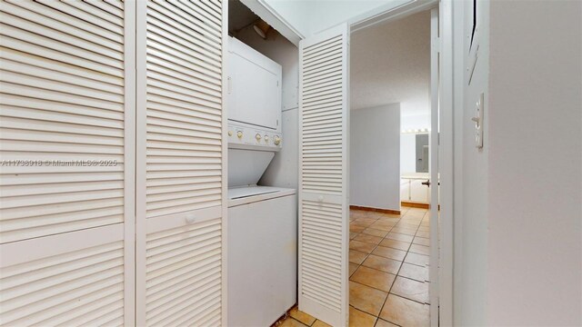 washroom featuring stacked washer and dryer and light tile patterned flooring