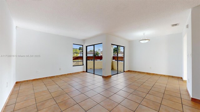 spare room with light tile patterned floors and a textured ceiling