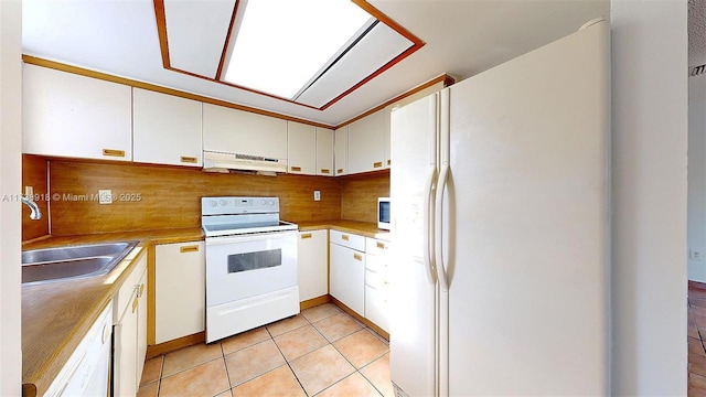 kitchen with sink, white appliances, light tile patterned floors, white cabinetry, and tasteful backsplash