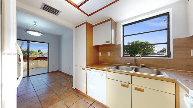 kitchen with light tile patterned flooring, sink, tasteful backsplash, decorative light fixtures, and dishwasher