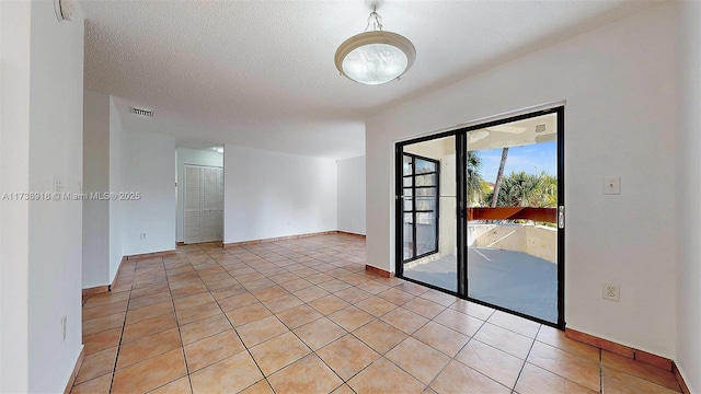 tiled empty room with a textured ceiling